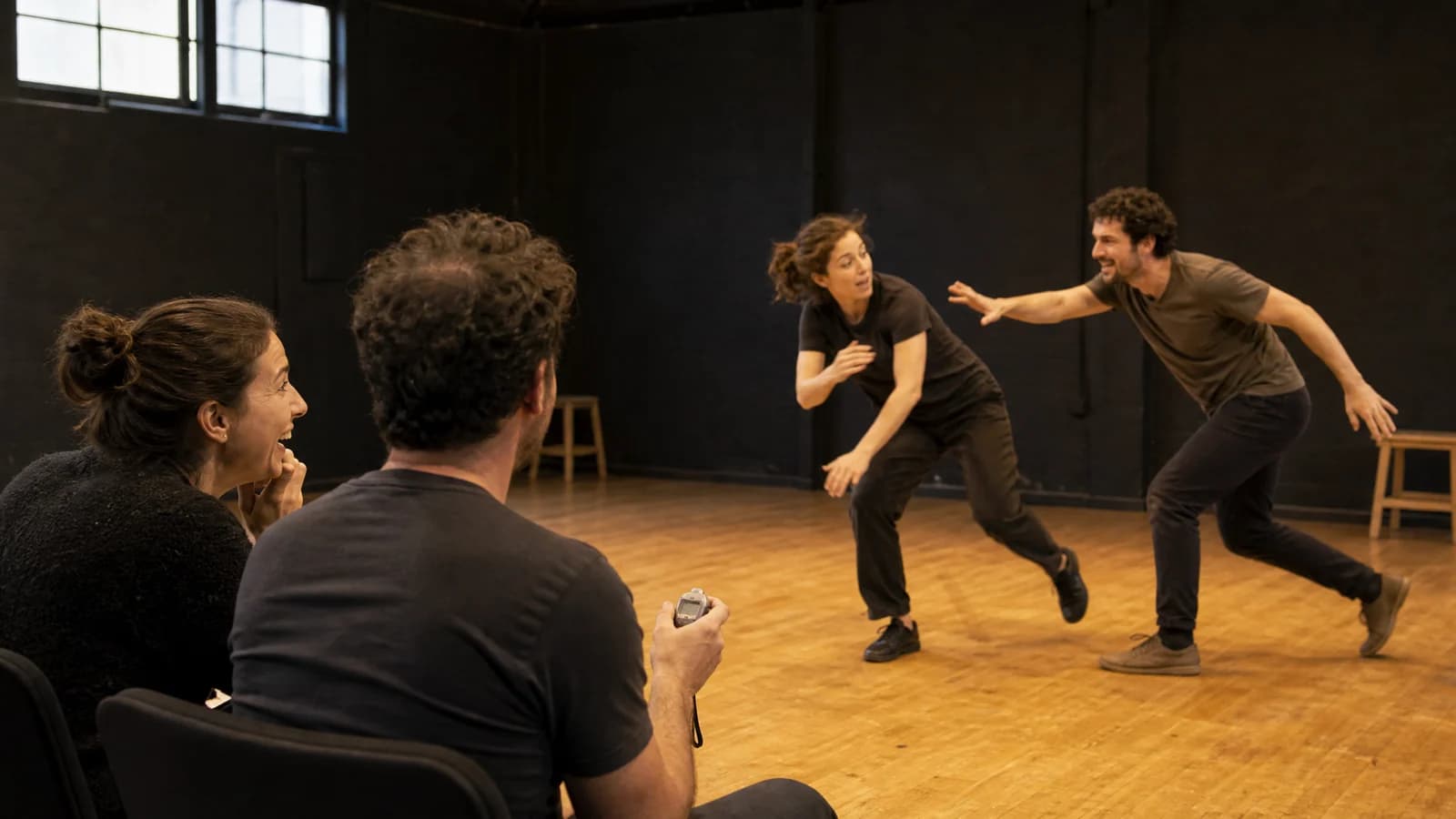 Screenwriter and director time actors rehearsing a physical scene on a sunlit stage